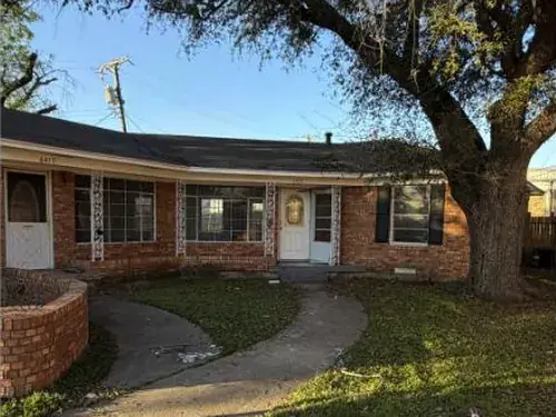Fachada de uma casa térrea de tijolos sob um carvalho